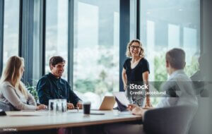Office colleagues having casual discussion during meeting in conference room. Group of men and women sitting in conference room and smiling.